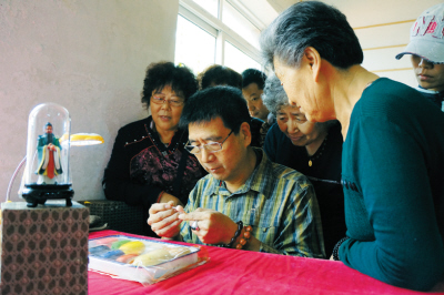 中國著名面塑大師、北京市非遺“郎派面塑”傳承人張寶琳在為游客展示面塑工藝。